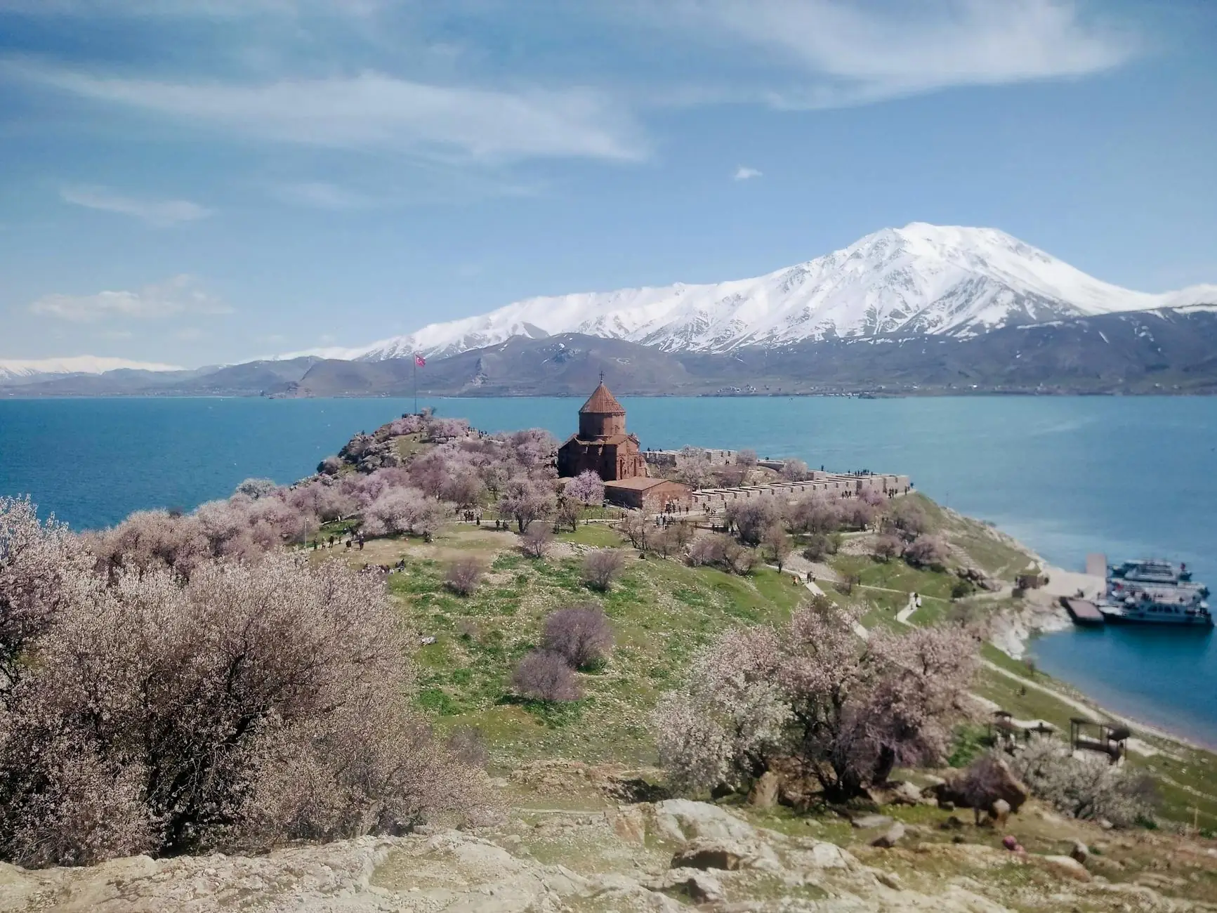 Akdamar Island in spring, with almond trees in blossom, the lake, and snowy peaks beyond