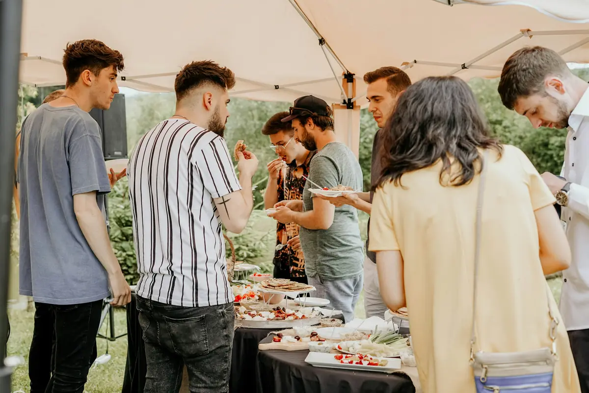 Young adults sharing a meal together outdoors under a canopy