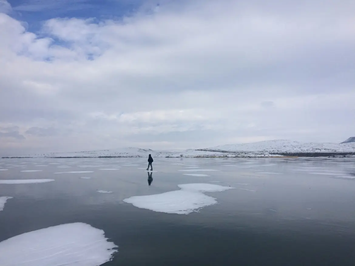 A person walking across frozen Çıldır Lake in Kars