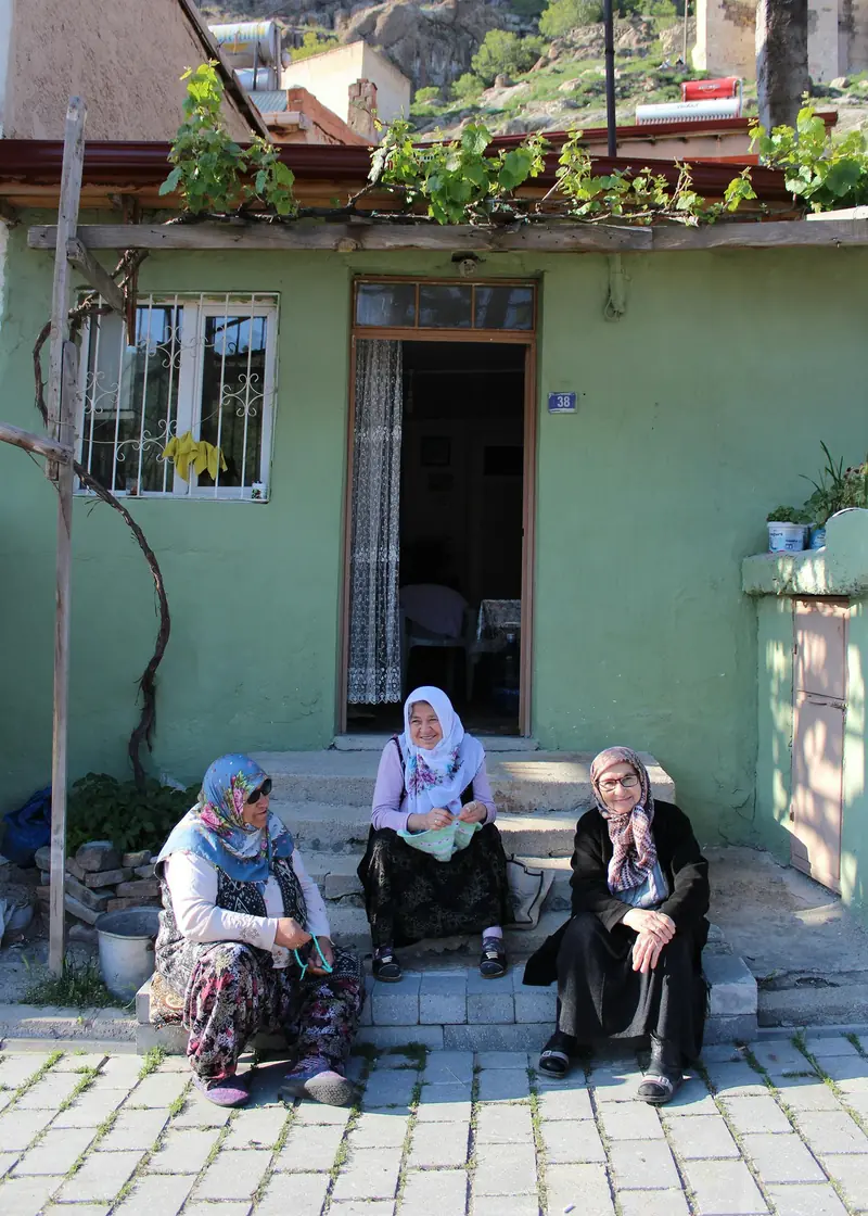 Three women sitting together on the steps of a house